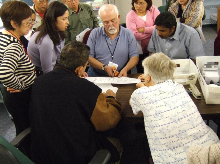 several people standing around a table while holding papers