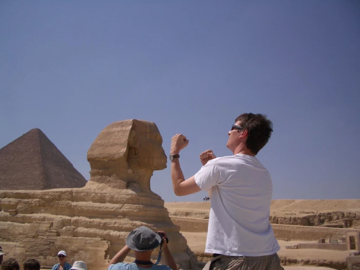 man standing with his hand out by an egyptian sphinx