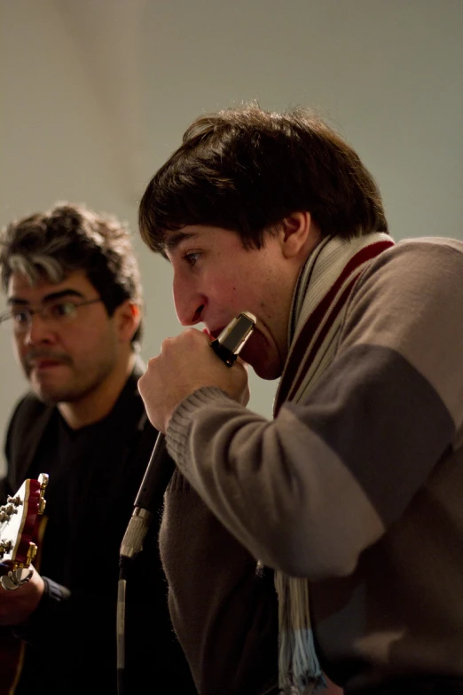 two men, one talking on the telephone, while holding an object in their hands