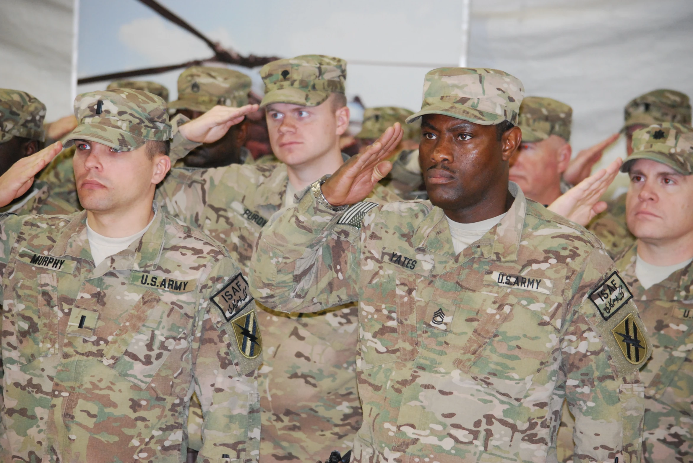 several army men salute their hands while in uniform