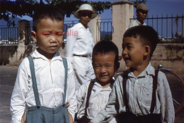 three small s and one older gentleman wearing suspenders and hat