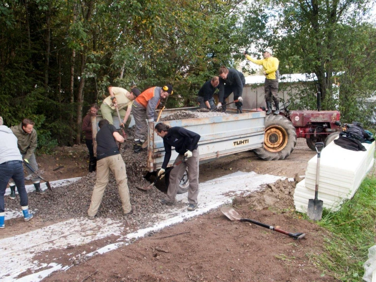 men working on the back of a truck as another man stands nearby