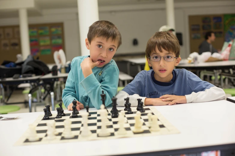 two s sitting at a table playing chess