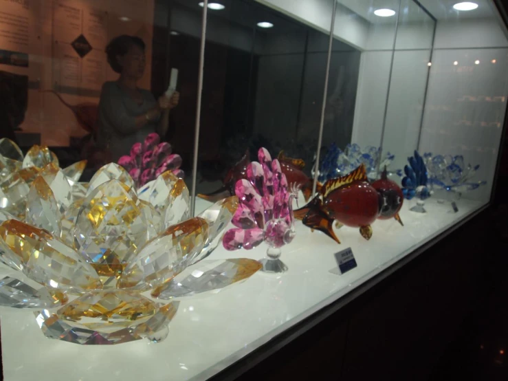 glass vases and ornaments on a counter in front of glass wall