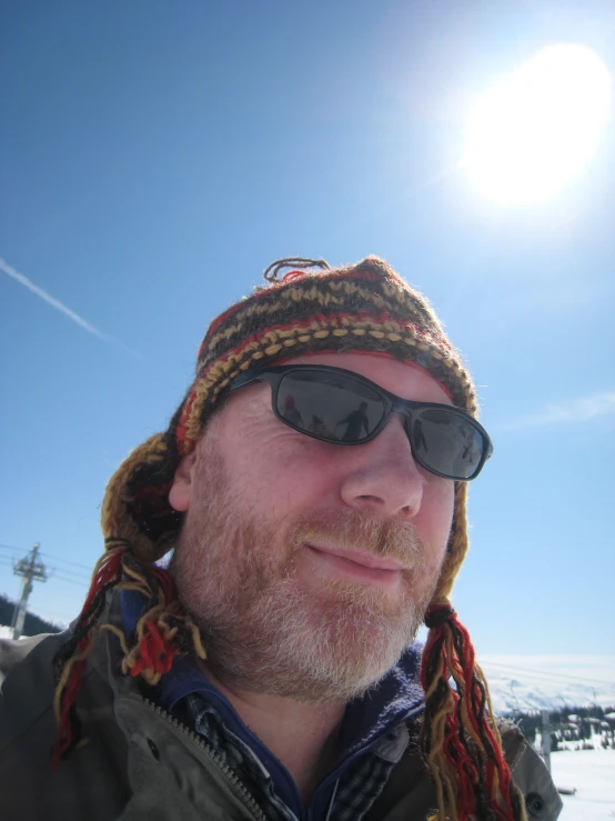 a man wearing sunglasses and a hat smiles for the camera