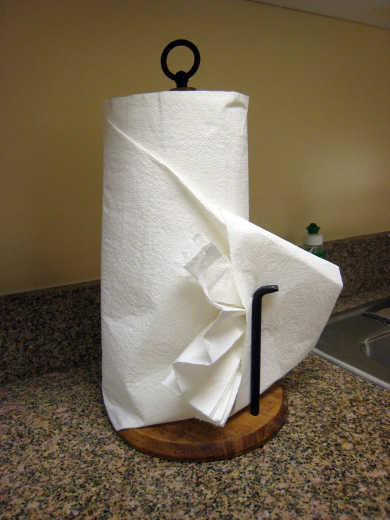 a black handle on top of a white roll of toilet paper