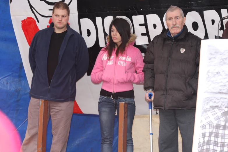 two men and a woman standing in front of a sign