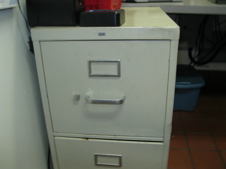 a filing cabinet with two containers on it's lid