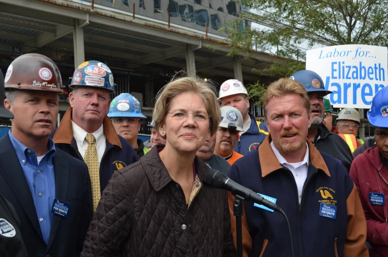 many people holding a microphone are gathered outside