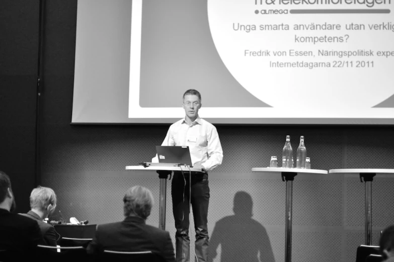 a man stands behind a podium speaking at the event