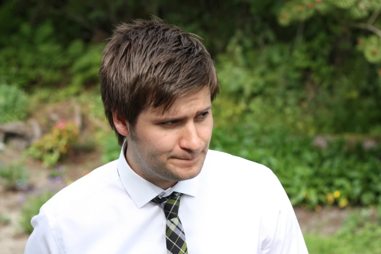 young man looking at camera while wearing a shirt and tie