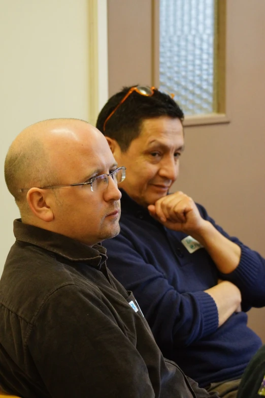 two men sit next to each other in a room