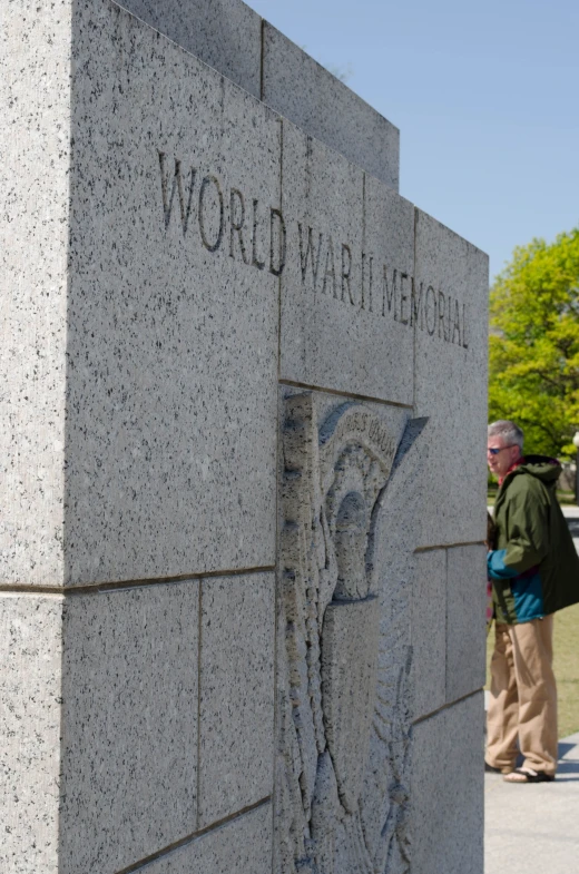 a couple of people standing by a stone wall