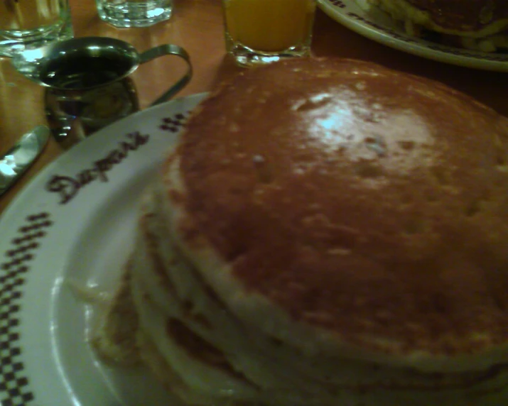 the stack of pancakes on the plate has one bite taken out of it