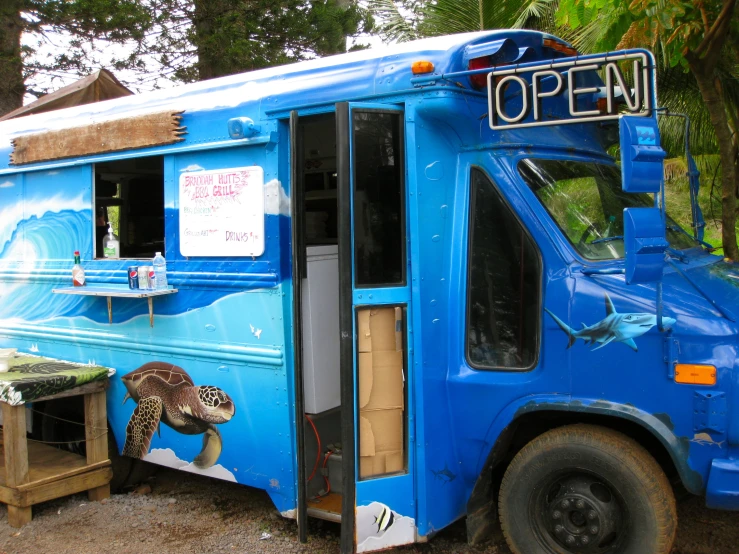 a blue bus parked in the street with its door open