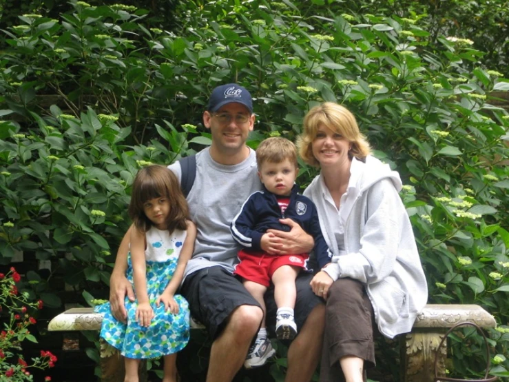 a family sits on a bench in a garden