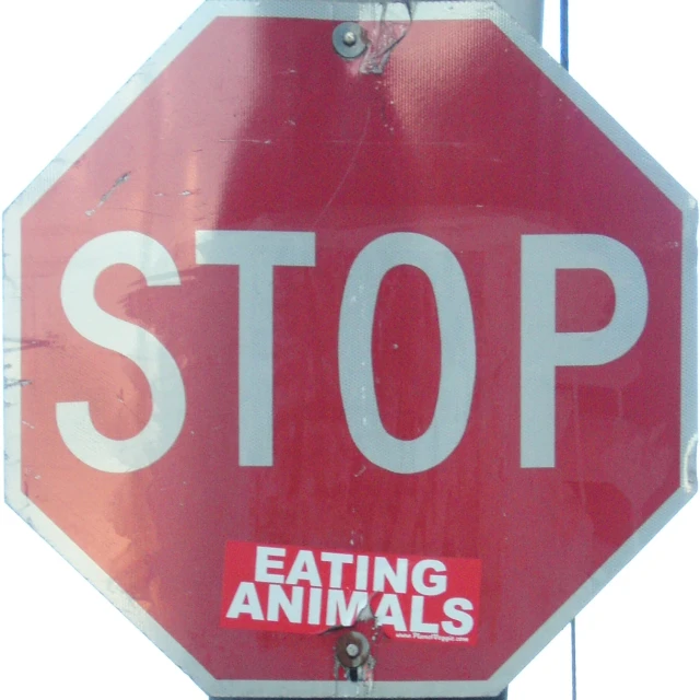 a stop sign with the words eating animals underneath it