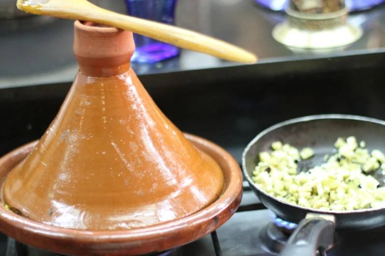 a clay pottery pot with a wooden spoon over it