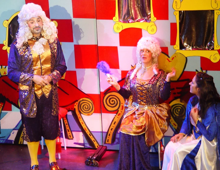 three people dressed in costumes on stage at a theatre
