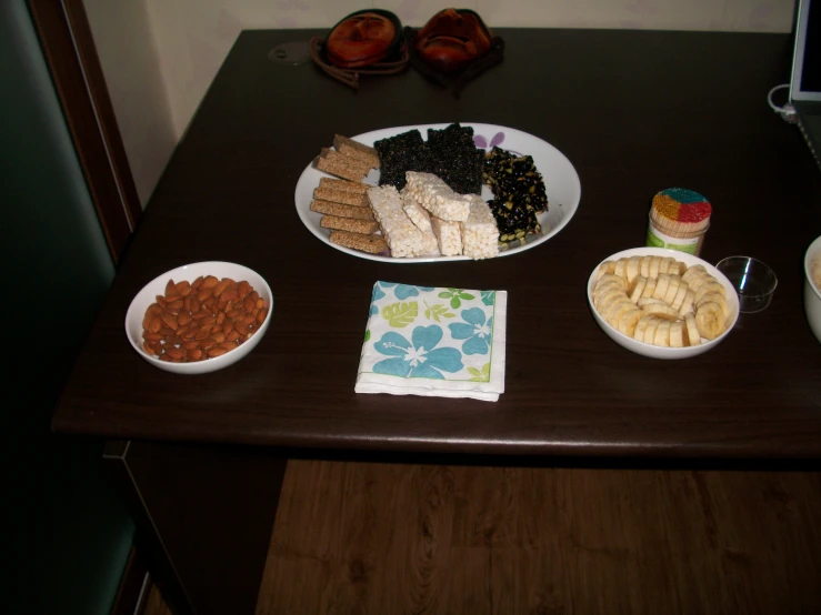 a wooden table topped with three plates full of snacks