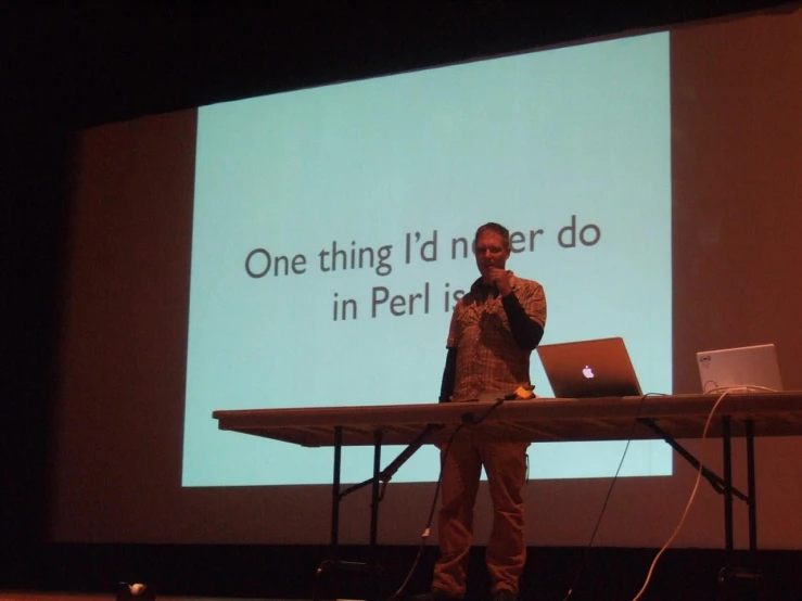 a man standing on a stage in front of a projector screen