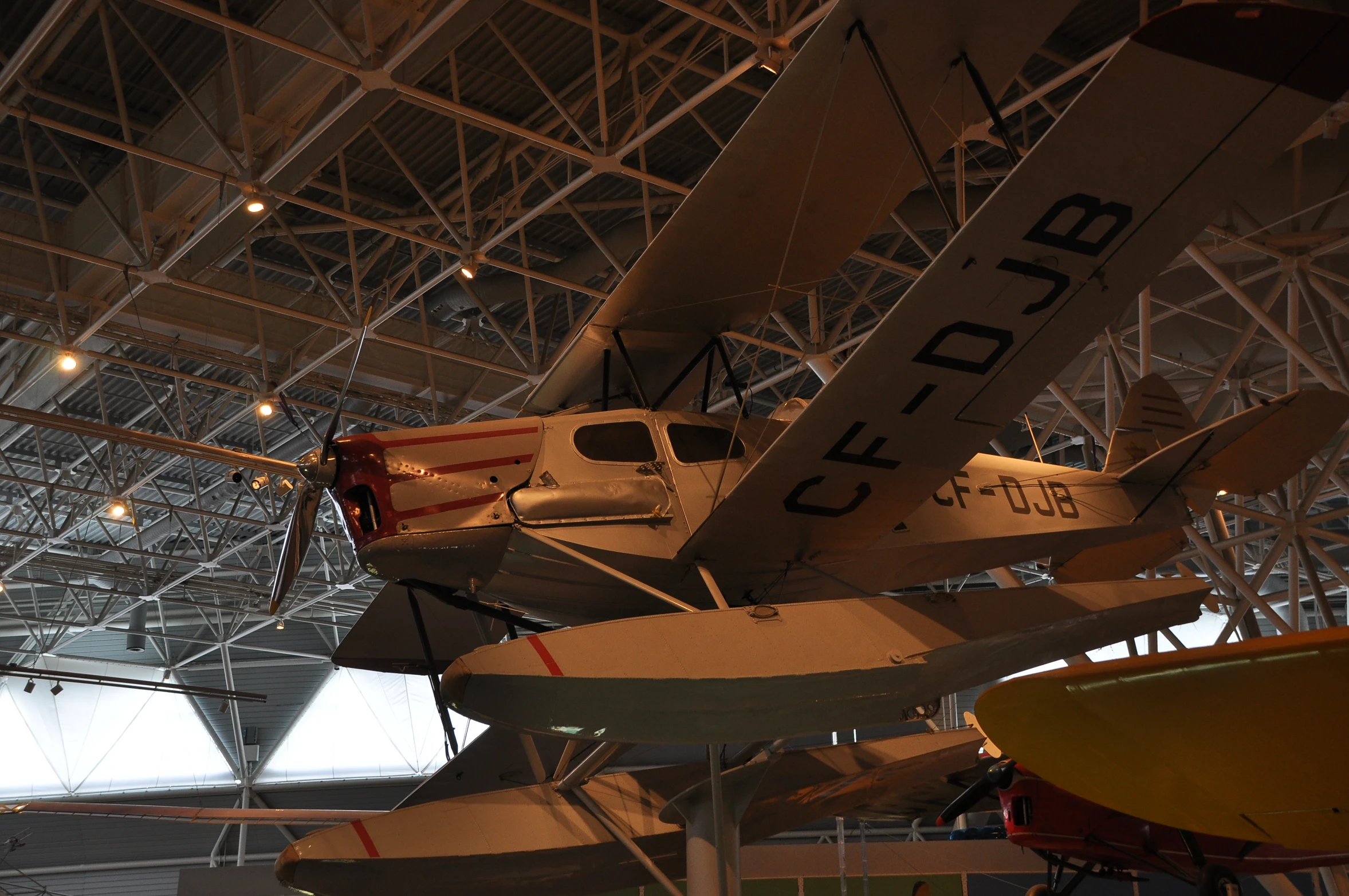 two airplanes in a hanger and people walking by