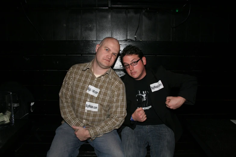 two men standing next to each other with their arms crossed