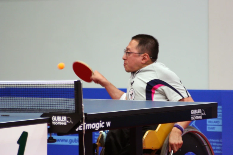 a man holding up his ping pong racket and ball