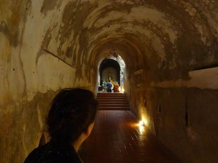 woman walking up a long dark passageway with light