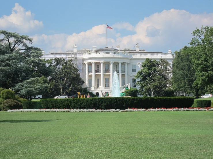 a large white building with two stories and trees around it