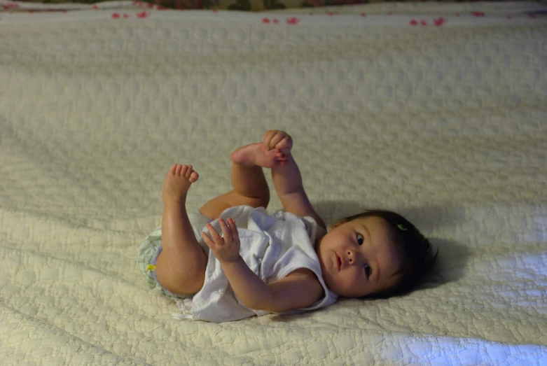 a baby is laying on its back on the bed