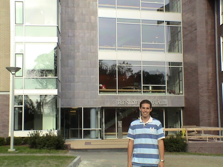 a guy posing for the camera while standing in front of a building