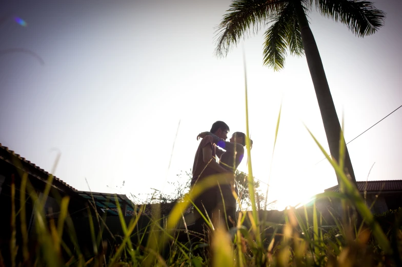 silhouette of two people near each other in tall grass