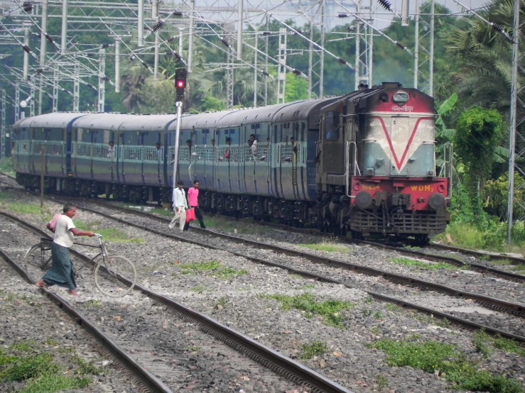 some people standing around while watching a train on the tracks