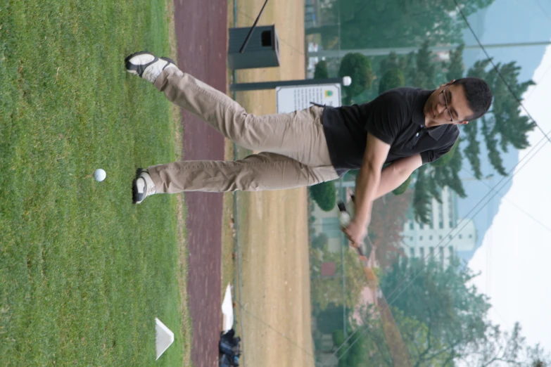 man holding club swinging in grassy area of park