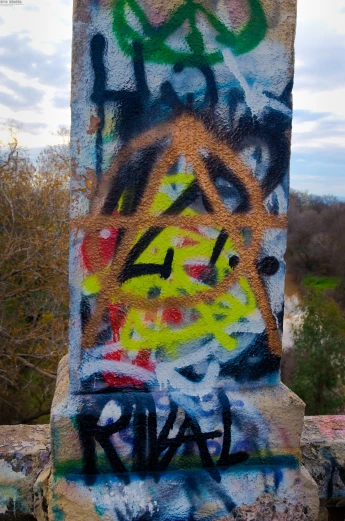 a very tall wall covered in graffiti near the forest