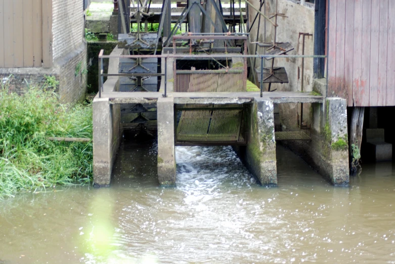 a small stream flowing under a rusty building