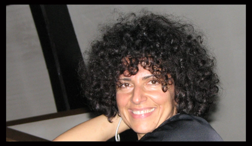 a woman with curly hair posing for a picture