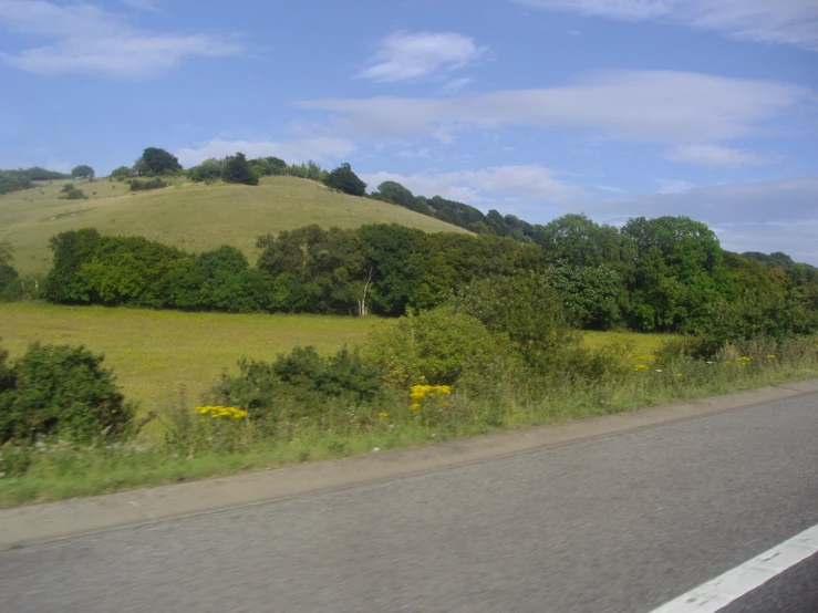 a grassy hill near a rural road on a sunny day