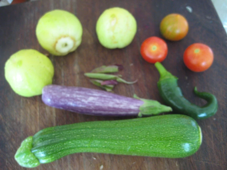 some veggies that include green beans, tomatoes and an eggplant