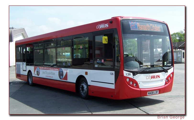 a long red bus parked in front of a building