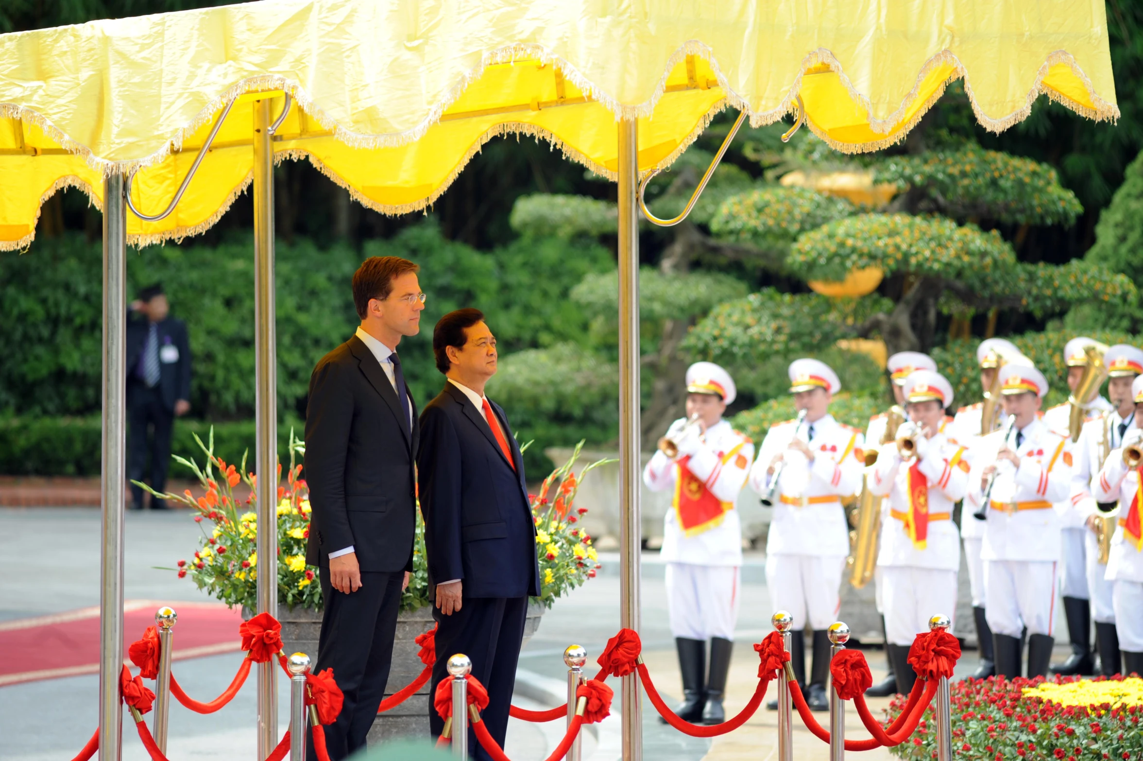 two men standing at a ceremony in front of a band