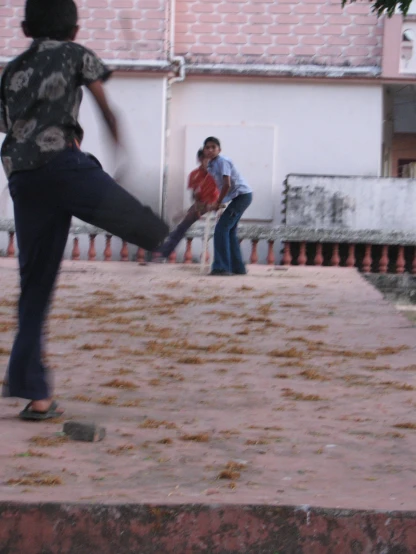 an image of a boy kicking a ball while his brother watches