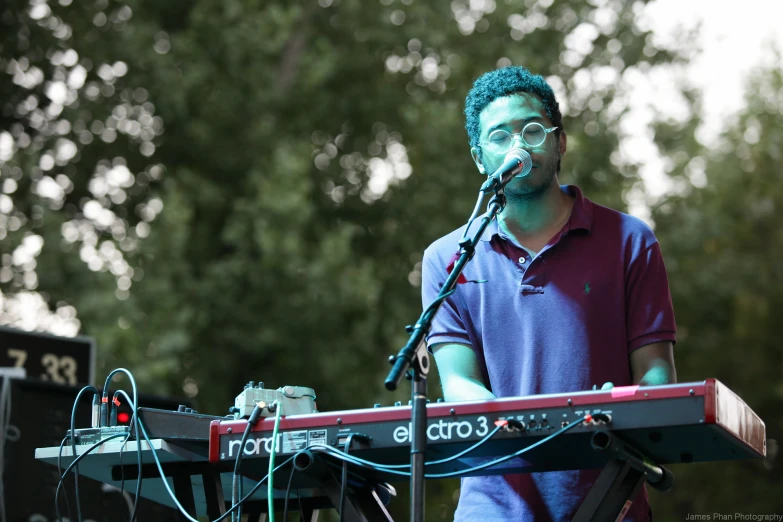 a man with green hair and glasses holding a keyboard