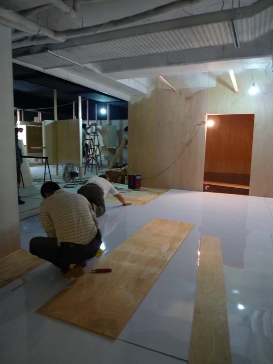 two people work on wood floors inside of a building