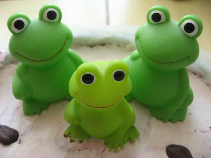 three green frog figurines sitting next to each other