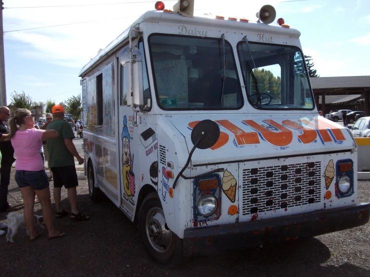 people standing outside of a food truck parked on the side of a street