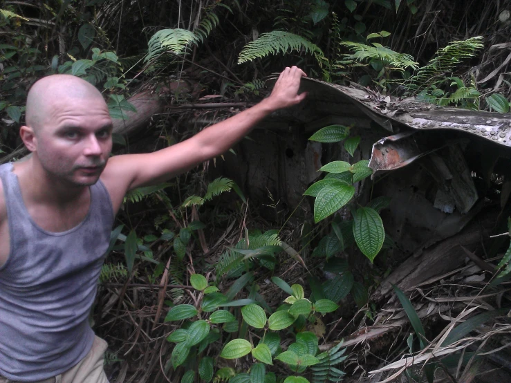 a man in the woods holding out his hand to a flying object