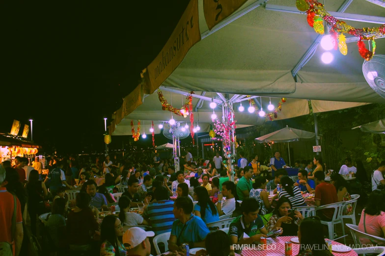 an outdoor gathering with many people eating at tables