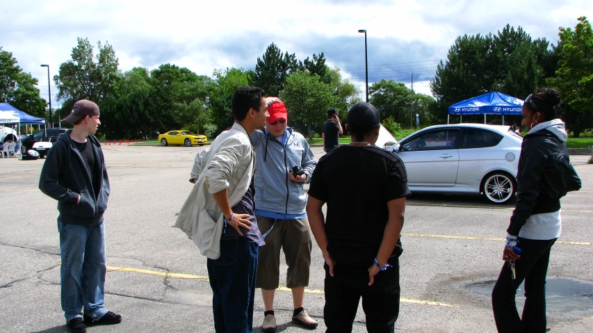 three men stand outside talking with one another